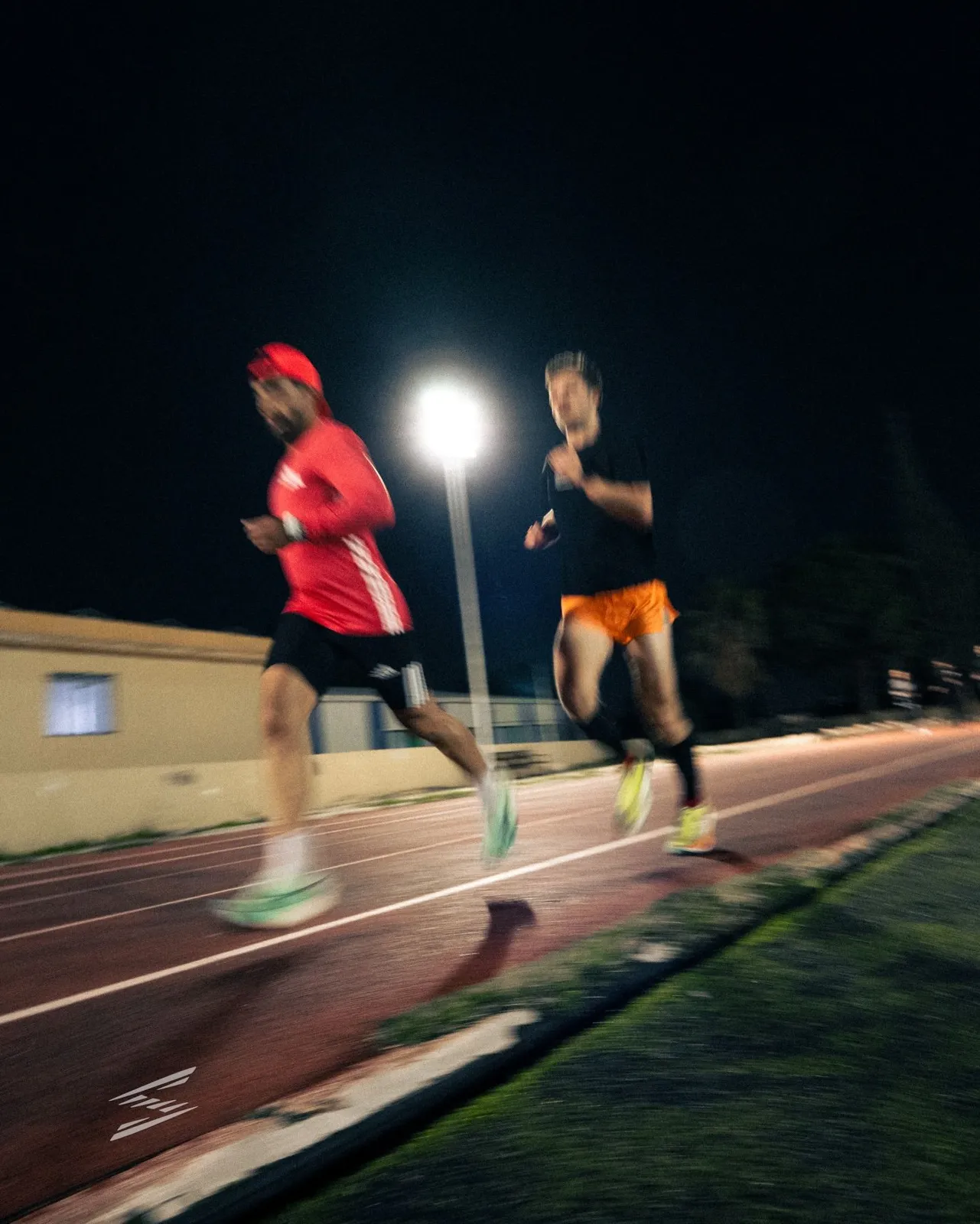 Two runners on the track under the floodlight