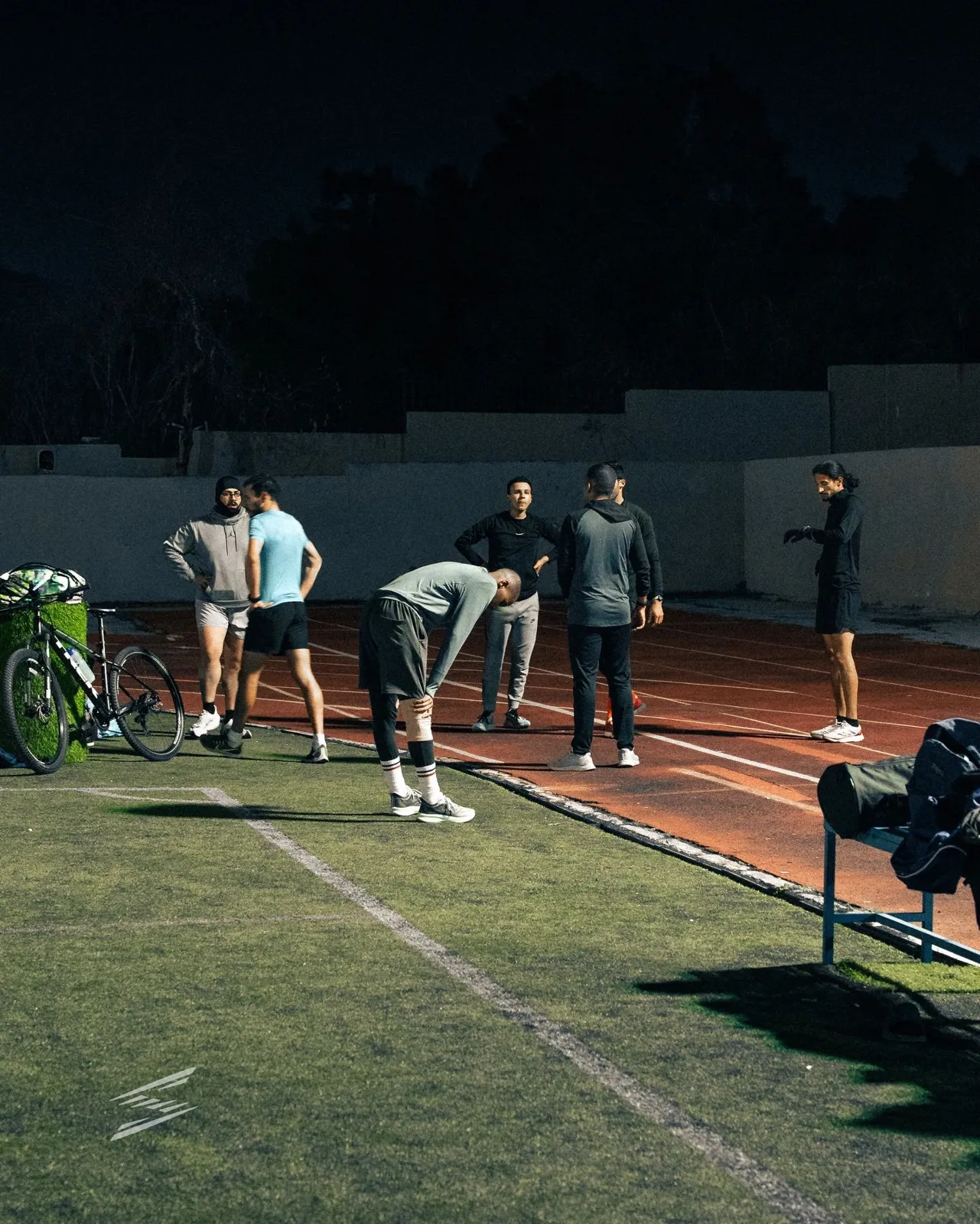 Striders runners resting between reps on the track at night